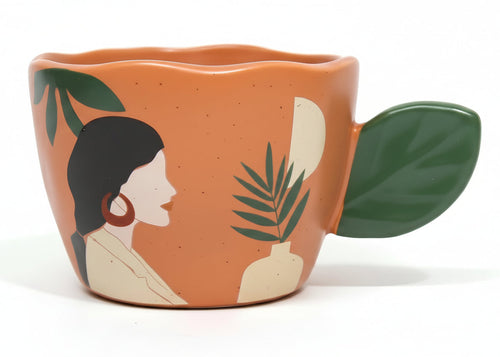Ceramic mug with artistic design of a woman's profile and leaves on a white background